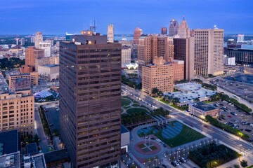 Naklejka premium Detroit skyline at twilight, showcasing urban architecture and parking lots. Evening city lights illuminate the skyscrapers. DOWNTOWN, DETROIT, MICHIGAN, UNITED STATES