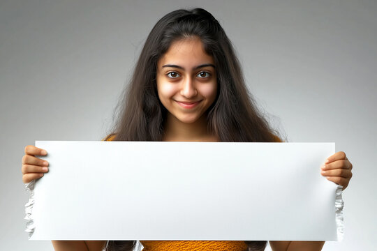 Young Indian model holding a blank board or rexine sheet, standing against a light grey background. For advertisements and commercial use.