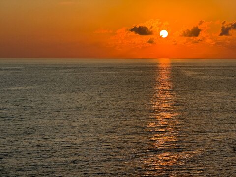 Sunset sky over ocean calm glittering water.
