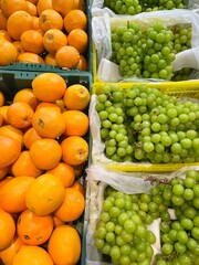 big green Korean grapes and oranges in boxes on the market counter