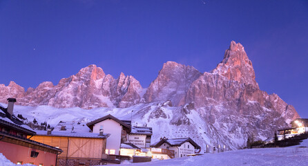 Pale di  San Martino e il Cimon della Pala sulle dolomiti viste dal Passo Rolle al tramonto tra luci suggestive e cielo blu nel paesaggio innevato