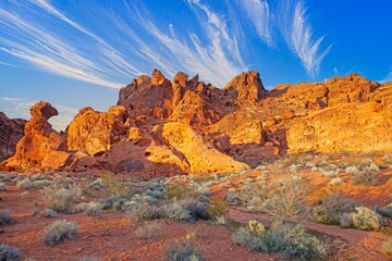 Red rock desert landscape with dramatic rock formations and vibrant blue sky at golden hour