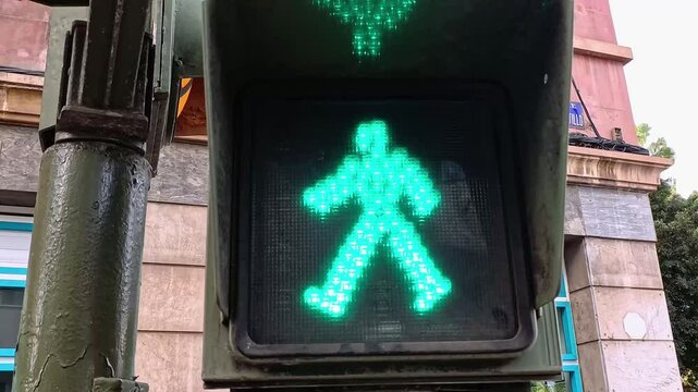 Close-up of a pedestrian traffic light. Green light flashing.