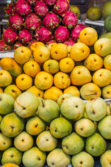 A colorful fruit display case made of mangoes and dragon fruit on display at the local market.