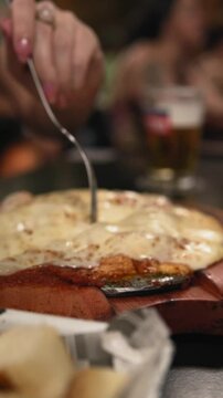 Slow motion closeup footage of a female hand using a fork to take a piece of beef parmigiana