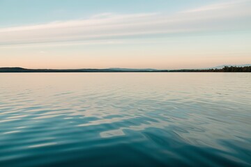 A serene landscape, predominantly characterized by a vast expanse of water that reflects the sky