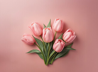 Obraz premium A delicate bouquet of six pale pink tulips arranged on a soft pink background. The tulips are tightly clustered, showcasing their elegant blooms and vibrant green leaves.