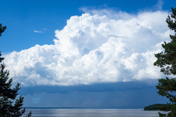 Big sky with puffy clouds and deep green trees.