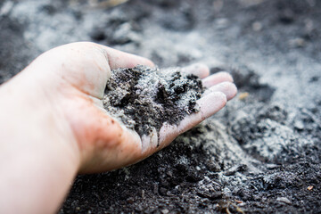 Hand holding rock dust for soil improvement in a raised garden bed
