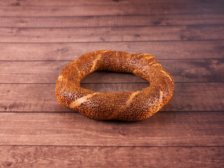 Turkish simit, fresh baked round bagel called Turkish simit on wooden table background, copy space. Traditional Turkey Istanbul breakfast snack close up photo. Bakery product with sesame seeds.