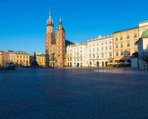 Obraz premium Krakow, Poland - 04.09.2020: St. Mary's Basilica and the empty Market Square during golden hour
