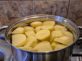 Freshly peeled potatoes soaking in water in a stainless steel pot, ready for cooking or preparation. Ideal for food recipes and culinary projects.