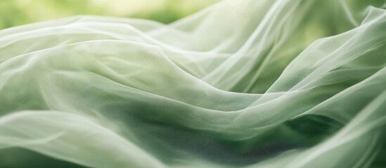 Obraz premium Delicate tulle fabric gracefully draped highlighting soft folds and textures against a serene green backdrop for color contrast and elegance.
