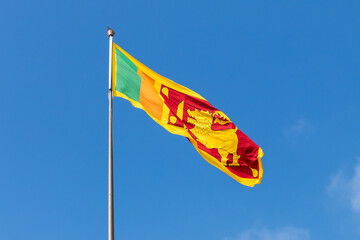Flag of Sri Lanka or the Sinha Flag is on a flagpole under blue sky
