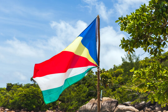 The flag of Seychelles is on the beach on a sunny summer day