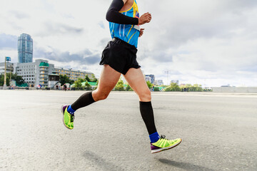 athlete runner in compression socks and sleeves running marathon on street