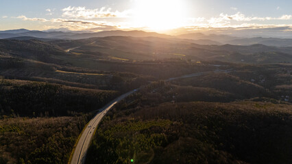 Aerial View of the Autobahn: Moving Cars and Summer Countryside Road in Austria, captured from a drone’s perspective, with the stunning wild forests of Austria in the background. Austria aerial