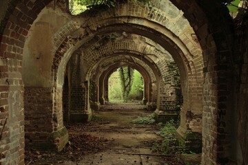 Naklejka premium Abandoned structure with weathered arches and exposed brick walls at sunset in a deserted location