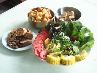 a set of healthy meal with chicken, potato, bread and fresh vegetable salad