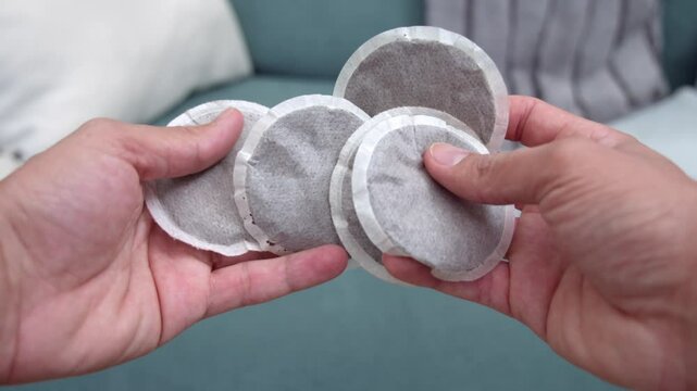 Man holding circular black teabags