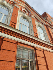 Metal security grilles adorn the windows of a red brick building, showcasing practical solutions for urban safety. The image reflects historic architecture integrated with modern security features.