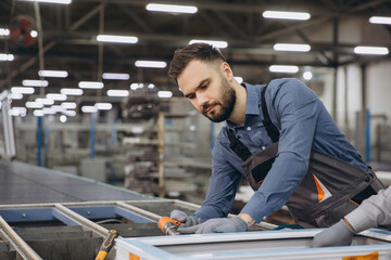 Factory worker assembling aluminum window frame on production line