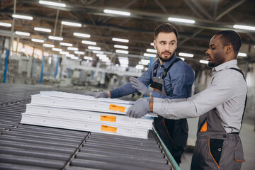 Factory workers moving pvc window frames on production line