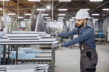 Factory worker handling aluminum and PVC window and door profiles