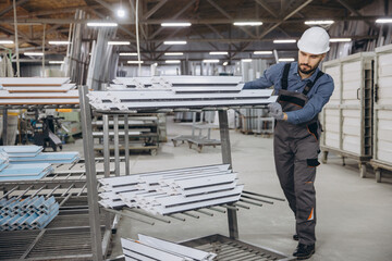 Factory worker moving aluminum profiles for pvc windows and doors production