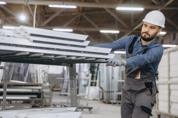 Fototapeta premium Factory worker moving aluminum profiles for windows and doors production