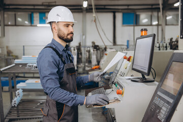 Factory worker operating machinery for aluminum and pvc windows and doors production