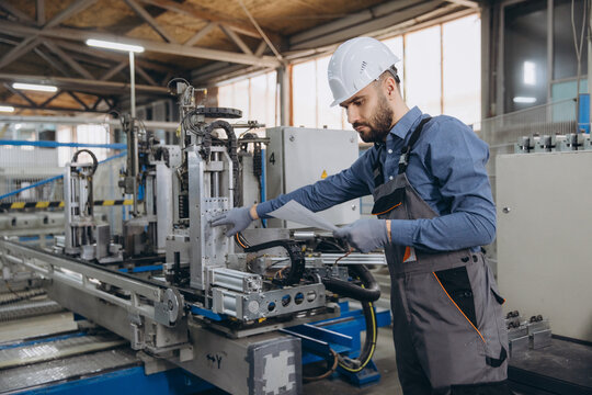 Factory worker operating industrial machinery for aluminum and pvc windows and doors production