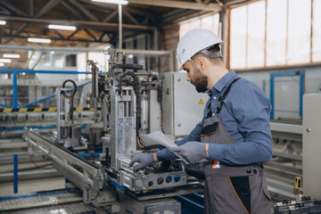Factory worker operating machinery for aluminum and PVC windows and doors production