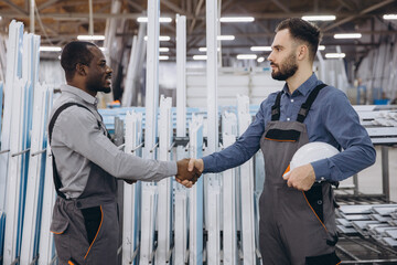 Factory workers shaking hands after finishing aluminum and pvc windows frames production