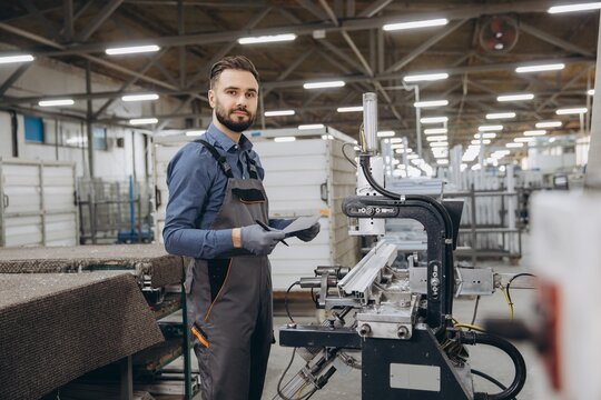 Factory worker controlling aluminum and pvc windows and doors production