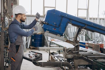 Factory worker operating industrial machine producing aluminum and pvc windows and doors