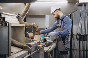 Factory worker operating machinery for aluminum and PVC windows and doors production