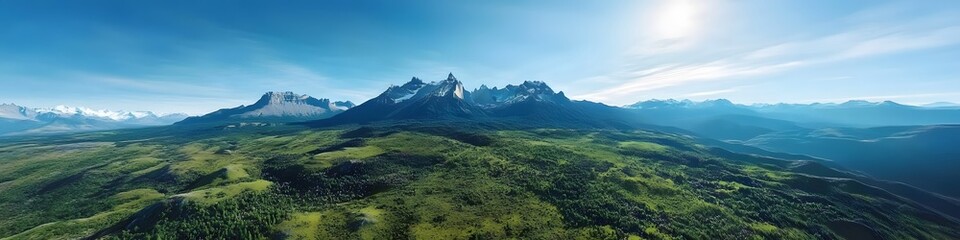 Fototapeta premium Aerial panorama of the Cuernos del Paine peaks surrounded by vibrant green valleys and wildflowers under a clear blue sky. in 4K resolution