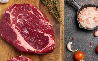 Raw beef steak chuck eye roll on wooden board. Spices for cooking Himalayan salt, thyme sprigs