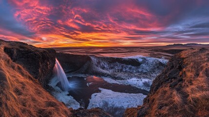Fototapeta premium Dramatic sunset over a frozen waterfall in Iceland.