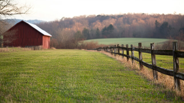 Red barn on a serene farm landscape with wooden fence and lush green grass under evening sky