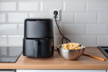 Trendy kitchen gadget air fryer machine cooking deep-fried potato. Lifestyle of new cooking, small...