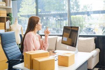 An Asian businesswoman sits at her desk, working on online sales and e-commerce marketing...