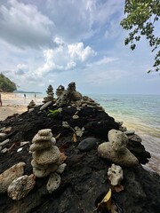 There is a substantial pile of rocks located on a beach beside the ocean