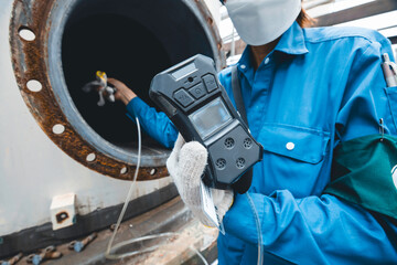 Worker female hand holding gas detector inspection safety gas testing at front manhole tank chemical