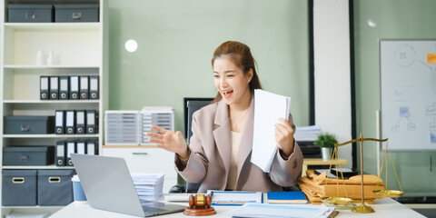 A young female lawyer sits at her desk in the office, providing online legal advice professionally....