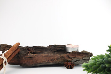 a small wooden log on white table with cinnamon sticks, star anise, pinecone and potpourri with tealight scented candles background white wall decorate in living room for display product