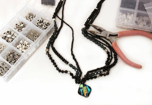 Jewelry-making tools and materials with colorful pendant.