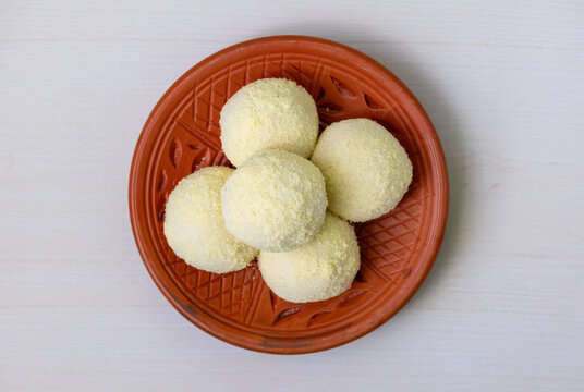 Tasty Kachagolla sweets served on a clay plate on a wooden background. Kanchagolla is a popular Bengali sweet delicacy known for its soft, spongy texture and subtle sweetness. Top view.