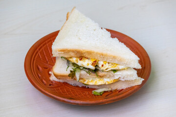 A nutritious egg sandwich, served on a traditional clay plate.